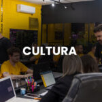 Pequena equipe de profissionais trabalhando alinhada em uma mesa de escritório, representando a cultura organizacional em pequenos negócios.