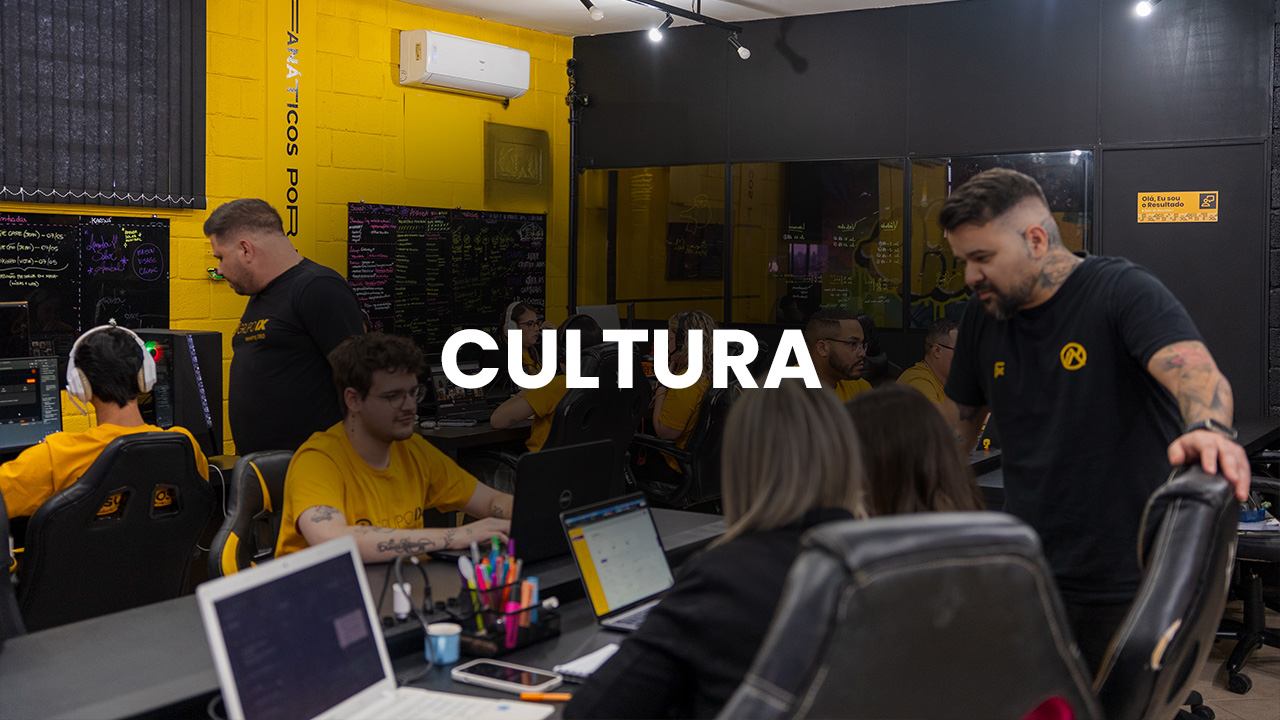 Pequena equipe de profissionais trabalhando alinhada em uma mesa de escritório, representando a cultura organizacional em pequenos negócios.